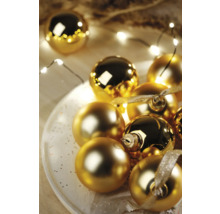 Dekoratívne zlaté vianočné gule na tanieri so svetelnou reťazou