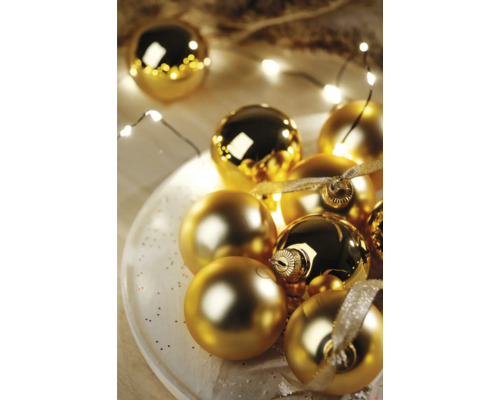 Dekoratívne zlaté vianočné gule na tanieri so svetelnou reťazou