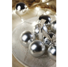 Dekoratívne vianočné gule s lesklým povrchom a stuhami na tanieri