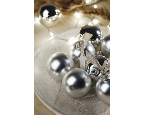 Dekoratívne vianočné gule s lesklým povrchom a stuhami na tanieri