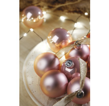 Ozdobné vianočné gule so stuhou na tanieri a svetelná reťaz