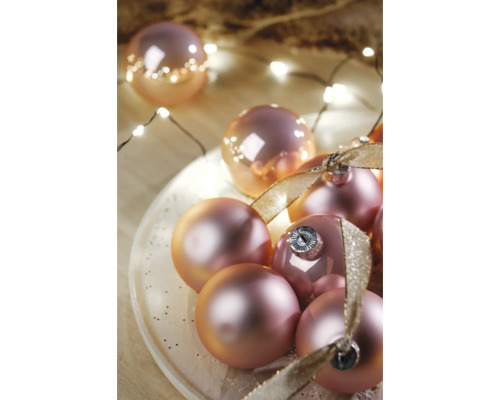 Ozdobné vianočné gule so stuhou na tanieri a svetelná reťaz