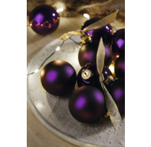 Dekoratívne fialové vianočné gule so stuhami na tanieri