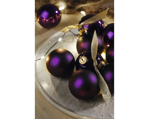 Dekoratívne fialové vianočné gule so stuhami na tanieri