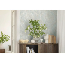 Dekoratívny interiér so vzorovanou tapetou, komodou, rastlinami a dekoratívnymi prvkami.