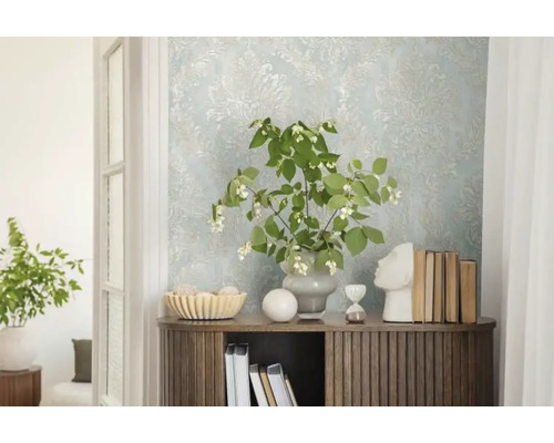 Dekoratívny interiér so vzorovanou tapetou, komodou, rastlinami a dekoratívnymi prvkami.