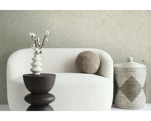 Dekoratívne bytové prostredie s pohovkou, príručným stolíkom, vázou s bavlnenými vetvami, vankúšom a úložným košom