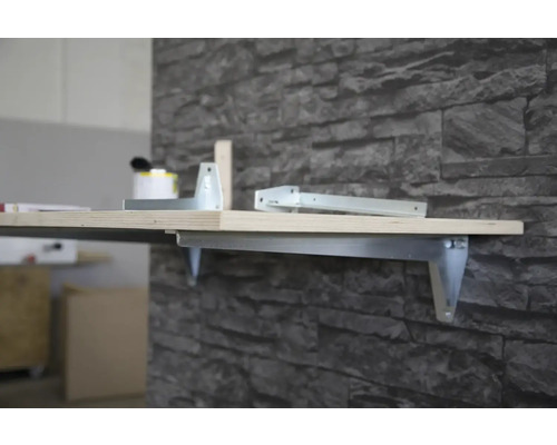 Nástenná polica s kovovým držiakom a drevenou doskou na kamennej stene