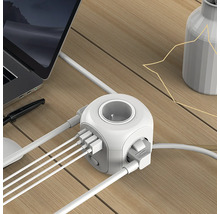 Zásuvková kocka s USB portami na stole s notebookom a vázou