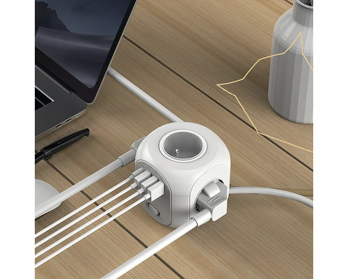 Zásuvková kocka s USB portami na stole s notebookom a vázou