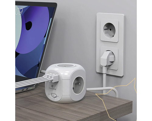 Zásuvková kocka s USB portami a zástrčkou v zásuvke vedľa notebooku