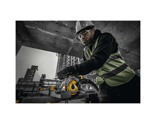 Muž s ochrannou prilbou a okuliarmi obsluhuje ručnú kotúčovú pílu značky DeWalt na stavenisku