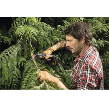 Muž strihá konáre stromu akumulátorovou prerezávacou pílou.