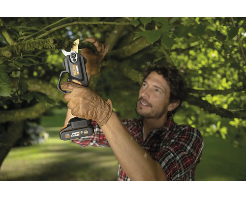 Muž strihá konár akumulátorovými nožnicami na konáre Worx Nitro.