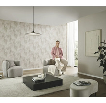 Moderná obývacia izba so vzorovanou tapetou, dve kreslá, konferenčný stolík a osoba