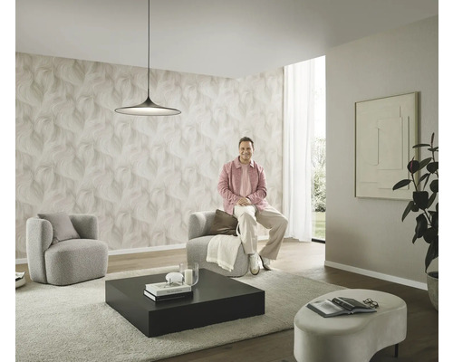 Moderná obývacia izba so vzorovanou tapetou, dve kreslá, konferenčný stolík a osoba