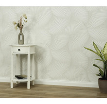 Scéna so vzorovanou tapetou, nočným stolíkom a izbovou rastlinou.