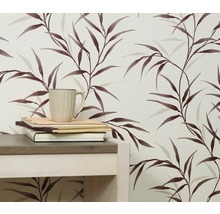 Detail steny s tapetou s listovým vzorom, stolom, knihami a šálkou.