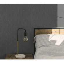 Spálňa so sivou štruktúrovanou tapetou, nočným stolíkom a lampou.