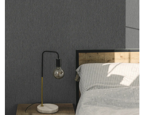 Spálňa so sivou štruktúrovanou tapetou, nočným stolíkom a lampou.