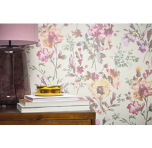 Detailný pohľad na stenu s kvetinovou tapetou, doplnenú lampou, knihami a miskou na drevenom nábytku.