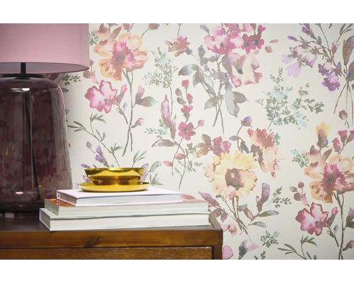 Detailný pohľad na stenu s kvetinovou tapetou, doplnenú lampou, knihami a miskou na drevenom nábytku.