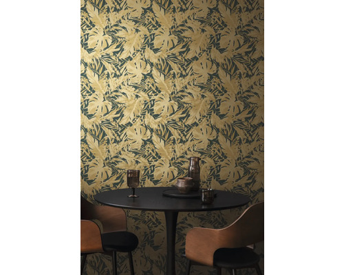 Izba s tapetou s motívom listov, jedálenským stolom a stoličkami.