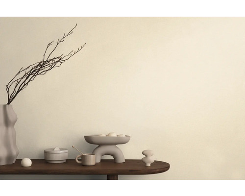 Dekoratívne aranžmán s vázou, vetvami, misou a keramickými objektmi na stole.