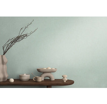 Dekoratívne usporiadanie na drevenom stole pred stenou s textilnou tapetou