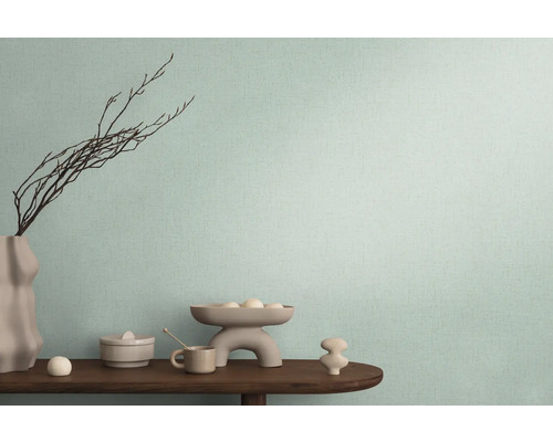 Dekoratívne usporiadanie na drevenom stole pred stenou s textilnou tapetou