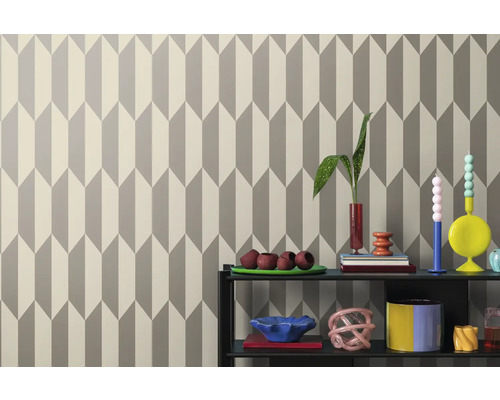 Tapeta s geometrickým šípovým vzorom za policou s dekoráciami.