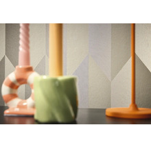 Detail vzorovanej tapety s geometrickými tvarmi v pozadí troch svietnikov.