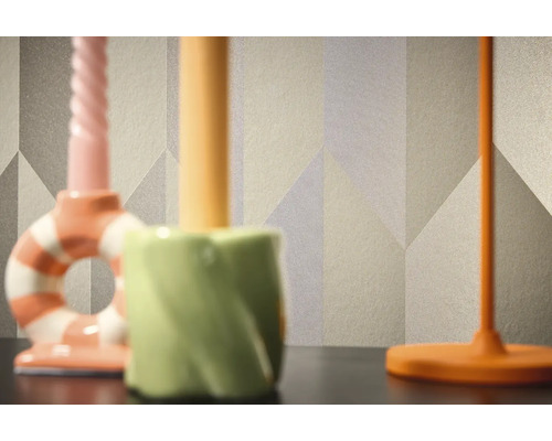 Detail vzorovanej tapety s geometrickými tvarmi v pozadí troch svietnikov.