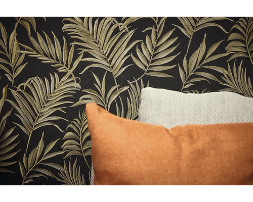 Detail steny s tapetou s motívom listov a dekoračnými vankúšmi