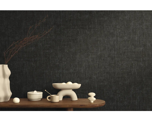 Štýlový dizajn izby s tmavou vliesovou tapetou a dekoratívnymi prvkami na drevenom stole.