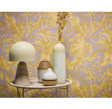 Dekoratívne zátišie so stolnou lampou a vázami pred tapetou s rastlinnými motívmi.