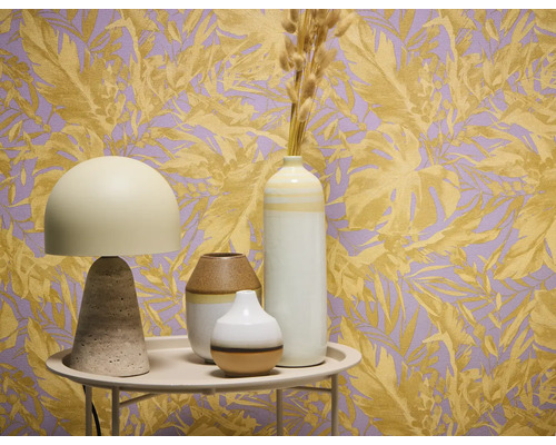 Dekoratívne zátišie so stolnou lampou a vázami pred tapetou s rastlinnými motívmi.