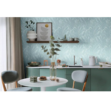 Svetlá miestnosť so stolom, stoličkami a kuchynským kútom pred stenou s tapetou s motívom listov.