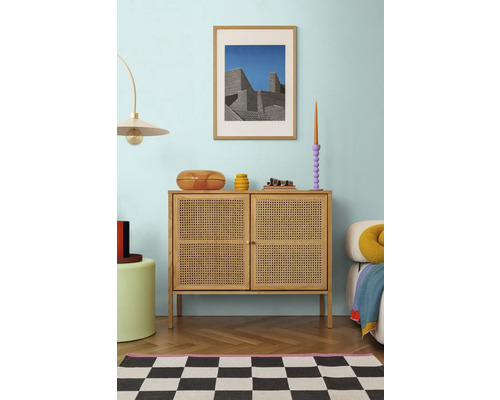 Interiér obývacej izby s komodou, dekoráciou a zarámovaným obrazom