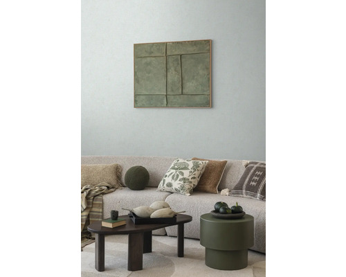 Obývacia izba s pohovkou, vankúšmi, konferenčným stolíkom a nástennou dekoráciou pre útulnú atmosféru