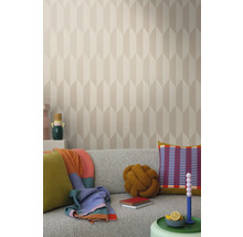 Svetlá obývacia izba so vzorovanou tapetou, sivou pohovkou a dekoratívnymi prvkami, ako sú vankúše a deky