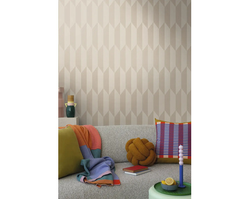 Svetlá obývacia izba so vzorovanou tapetou, sivou pohovkou a dekoratívnymi prvkami, ako sú vankúše a deky