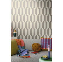 Obývacia izba s geometrickou tapetou v šedej a bielej farbe za sivou pohovkou