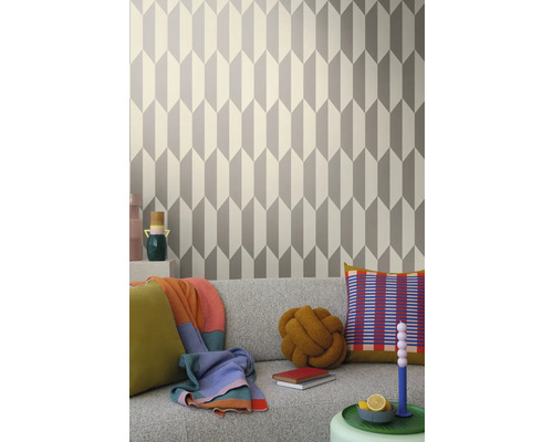 Obývacia izba s geometrickou tapetou v šedej a bielej farbe za sivou pohovkou