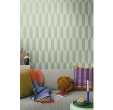 Obývacia izba so sivou pohovkou, vankúšmi, prikrývkami a stenou s geometrickou tapetou