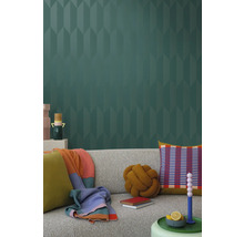 Obývacia izba so sivou pohovkou, vankúšmi, prikrývkami a vzorovanou tapetou pre štýlový interiér.