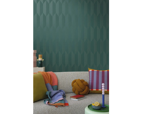 Obývacia izba so sivou pohovkou, vankúšmi, prikrývkami a vzorovanou tapetou pre štýlový interiér.