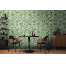 Obývacia izba s jedálenským stolom, stoličkami, regálom, skriňou a tapetou s rastlinným vzorom.