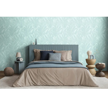 Spálňa s posteľou, nočnými stolíkmi a tapetou s motívom listov pre relaxačnú atmosféru.