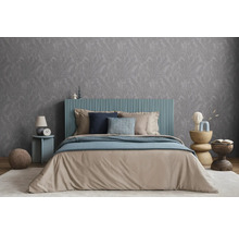 Spálňa s manželskou posteľou, nočným stolíkom a vzorovanou tapetou pre pokojnú atmosféru.